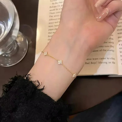 Bracelet NovaPick doré en acier inoxydable avec motifs trèfle sertis de zircons brillants porté au poignet